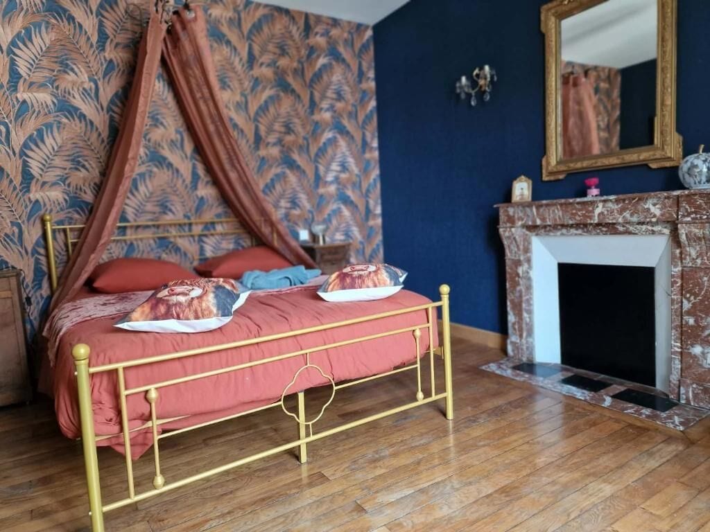 Een kamer met een hemelbed, een open haard en behang met een patroon.