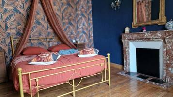 Een kamer met een hemelbed, een open haard en behang met een patroon.