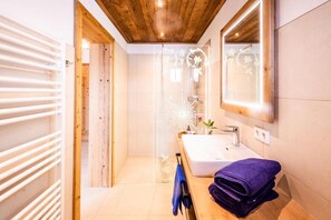 A modern bathroom with a wooden ceiling, a glass shower enclosure, a white sink, and a mirror. - Ferienhaus Mandlberggut by Apart4you (Radstadt)