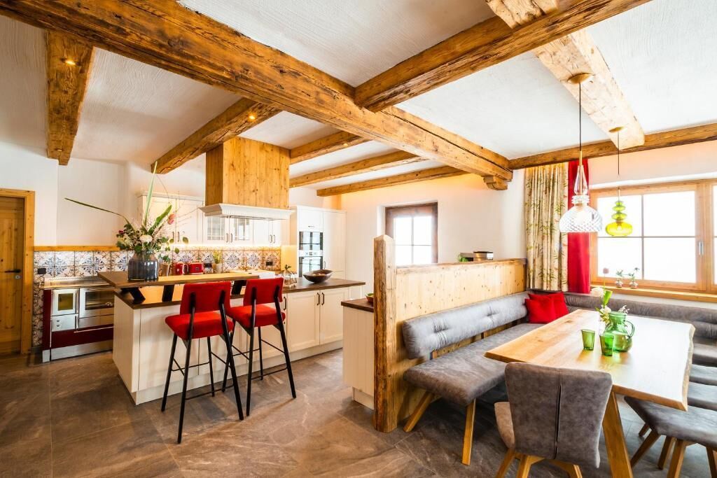 Une cuisine dotée d’un îlot central, de tabourets de bar et d’un coin repas avec des bancs et une table.