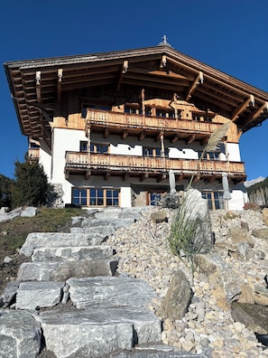 Ein mehrstöckiges Holzhaus mit Balkonen vor blauem Himmel.