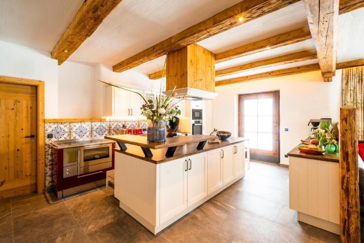 A kitchen with wooden beams, a central island, and a tiled backsplash.