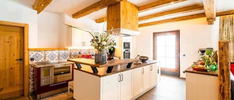 A kitchen with wooden beams, a central island, and a tiled backsplash.