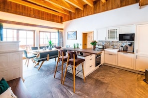 A modern kitchen with white cabinets, a wooden island, and a dining area with chairs.