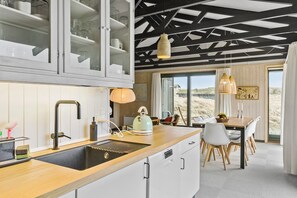 A modern kitchen with a wooden countertop, a sink, and a dining area with a table and chairs.