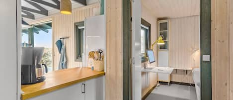 Una cocina moderna con armarios de madera, una cafetera y un ventanal con vistas a un paisaje natural.