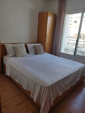 A bedroom with a bed, a wardrobe, and a window with a view of the outside. - Studio meublé à bèlvedère (Casablanca)