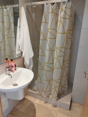 A bathroom with a white sink, a mirror, a shower curtain with a geometric pattern, and a towel hanging on the wall. - Studio meublé à bèlvedère (Casablanca)