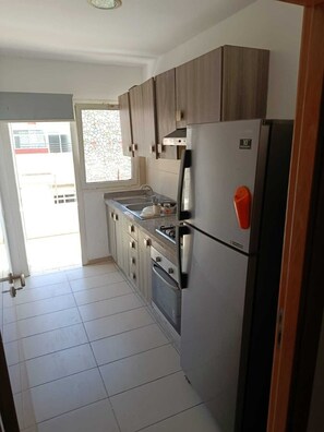 A kitchen with a refrigerator, stove, and cabinets. - Studio meublé à bèlvedère (Casablanca)