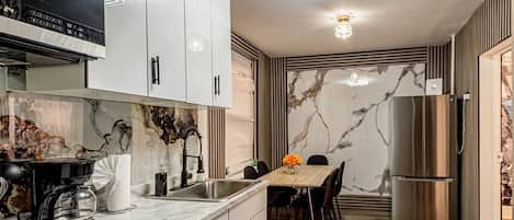 Una cocina moderna con estufa integrada, cafetera y refrigerador.