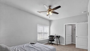 A bedroom with a bed, a desk, a chair, a ceiling fan, and a door. - Fresh 1-bedroom layout (Princeton)