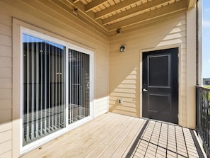 A covered outdoor area with a sliding glass door, a black door, and a small light fixture. - Fresh 1-bedroom layout (Princeton)