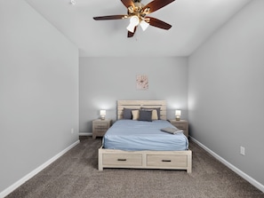 A bedroom with a bed, nightstands, a ceiling fan, and a wall-mounted light fixture. - Fresh 1-bedroom layout (Princeton)