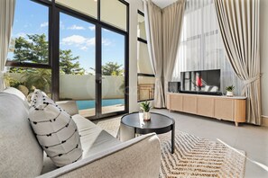 A modern living room with a sofa, a coffee table, and a TV on a wooden cabinet.