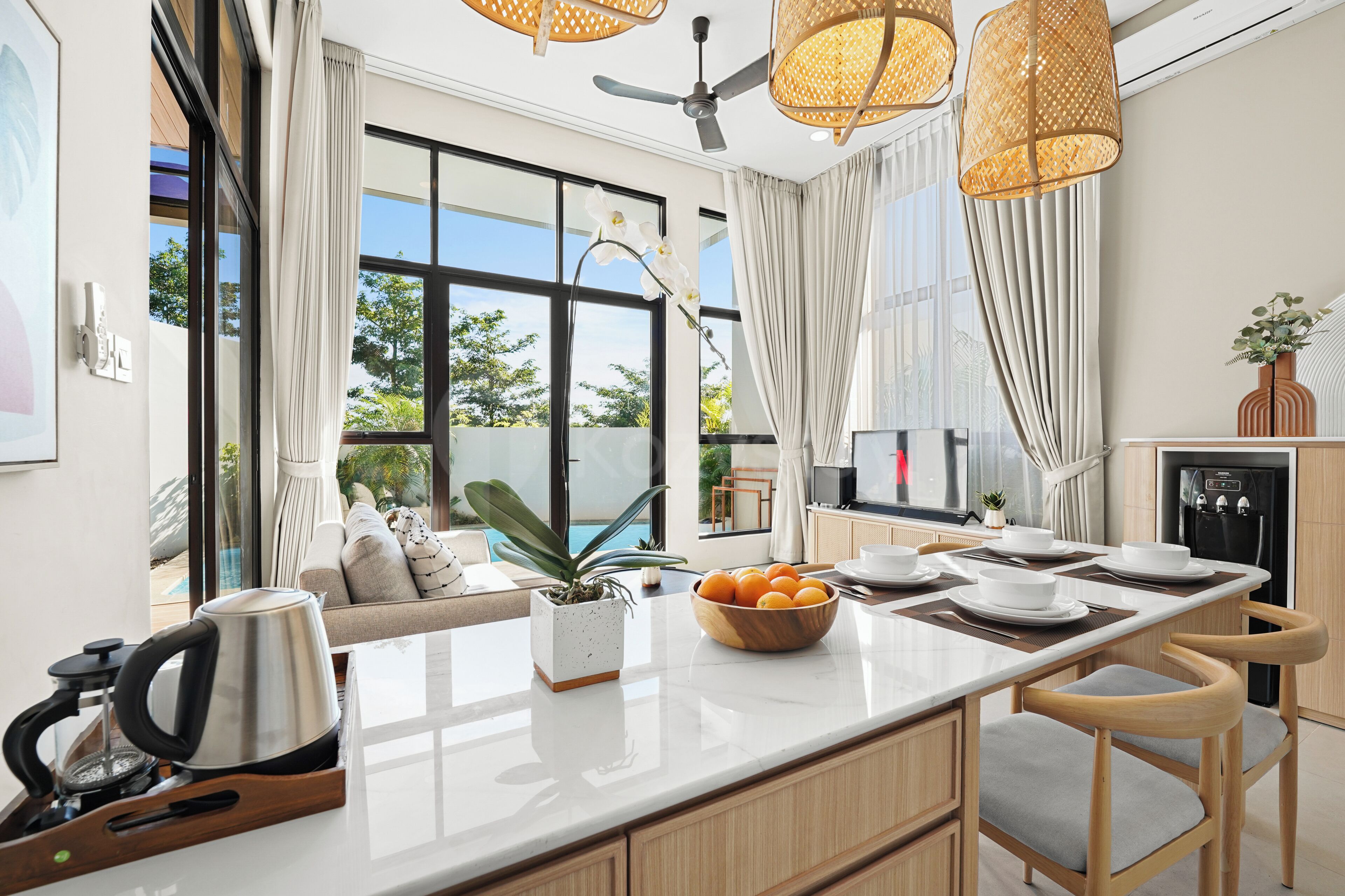 A modern kitchen with a large island, a coffee maker, and a bowl of oranges.