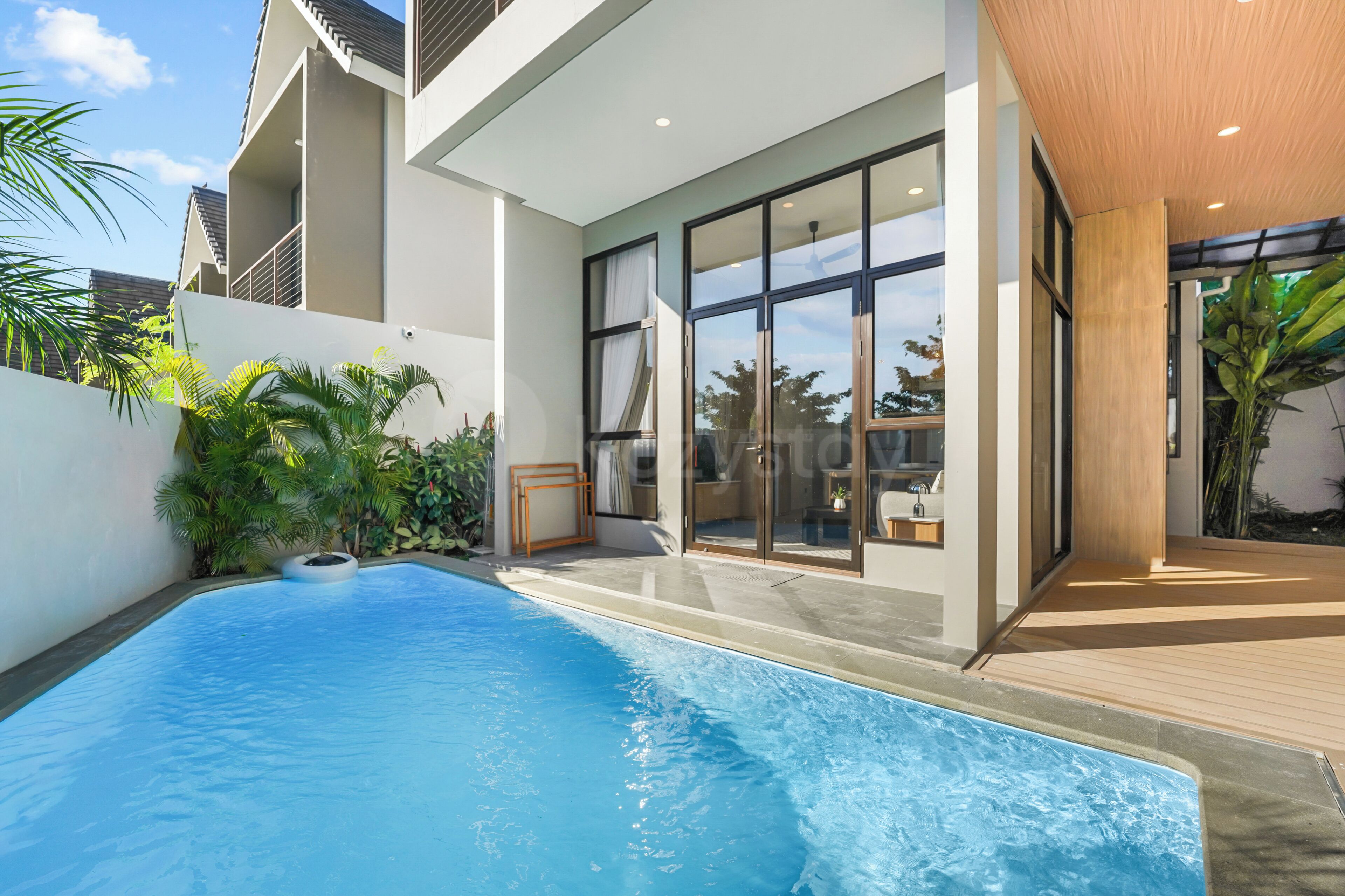A modern house with a swimming pool, large windows, and a wooden deck.
