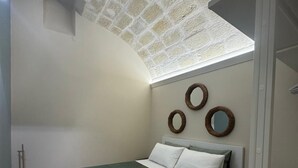 A bedroom with a bed, a wall-mounted mirror, and a broom. - Apartment in the heart of the city (Taranto)