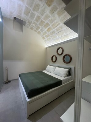 Ein Schlafzimmer mit einem Bett, einem Wandspiegel und einem Besen.