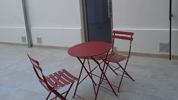 A patio with a table and two chairs, a door, and a window. - Apartment in the heart of the city (Taranto)