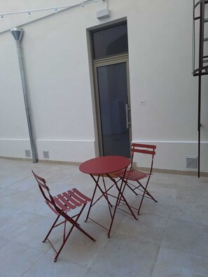 A patio with a table and two chairs, a door, and a window. - Apartment in the heart of the city (Taranto)