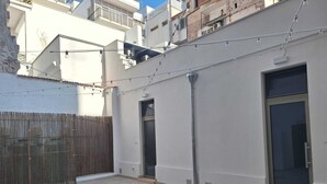 A courtyard with a tiled floor, a wooden fence, and a building with a large door and windows. - Apartment in the heart of the city (Taranto)
