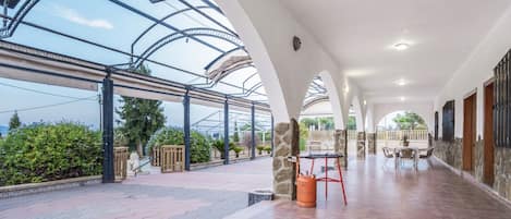 A covered outdoor area with a patio, a table with chairs, and a gas cylinder.