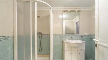 Baño con cabina de ducha, lavamanos y espejo.