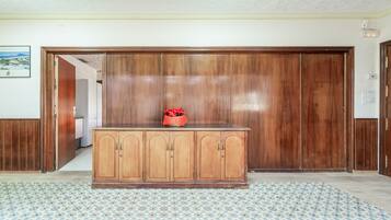 Une pièce avec un meuble en bois, un parquet à motifs et une porte donnant sur une autre pièce.