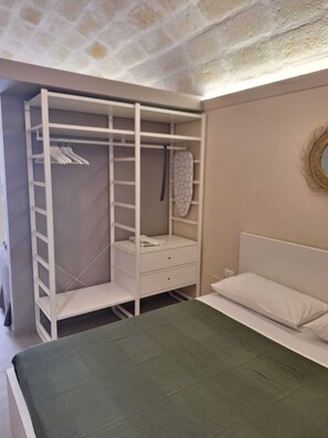 A bedroom with a bed, a wardrobe, and a bedside table. - Furnished studio apartment for rent on the ground floor. (Taranto)