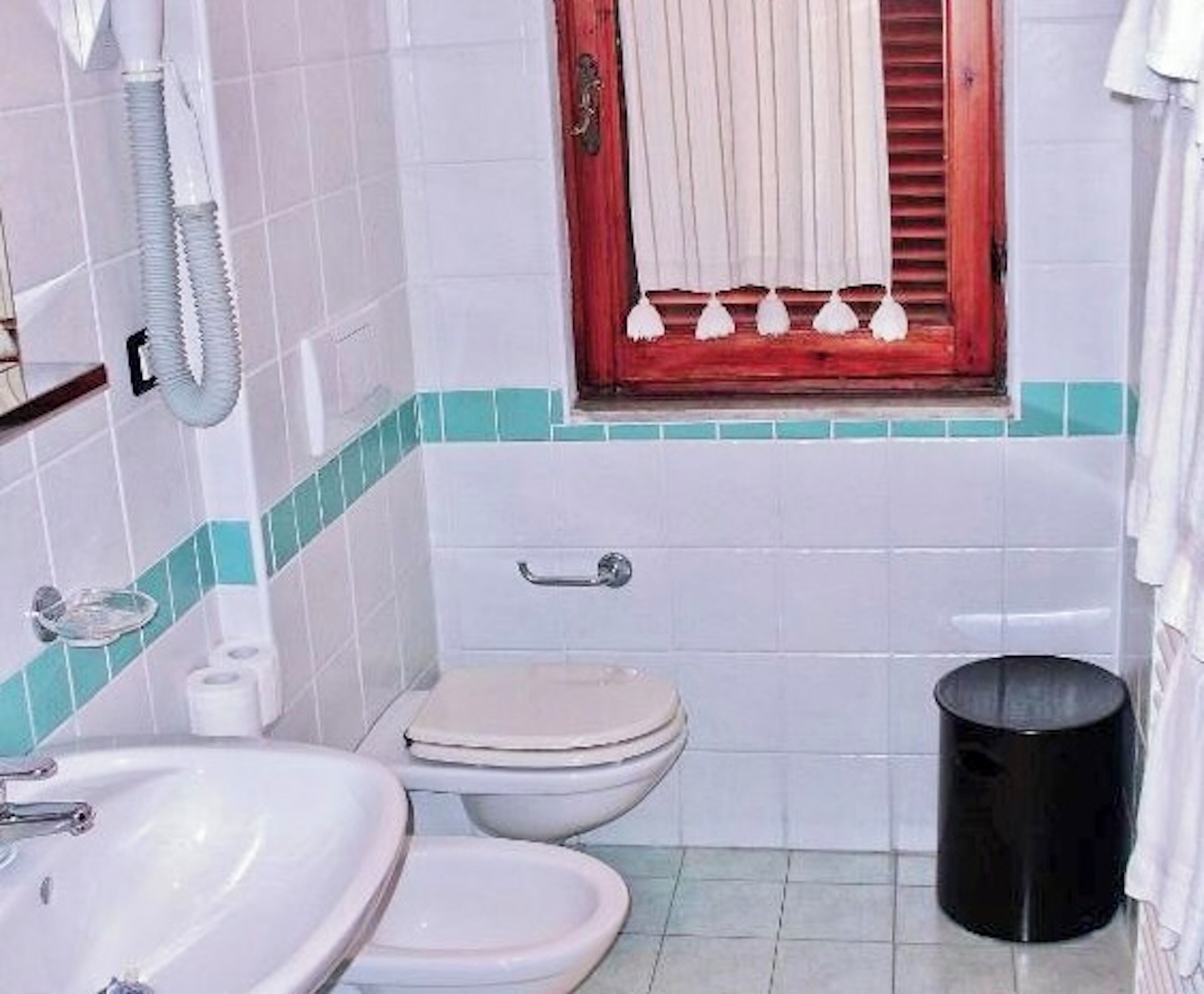 Ein kleines Badezimmer mit Toilette, Waschbecken und einem Mülleimer.