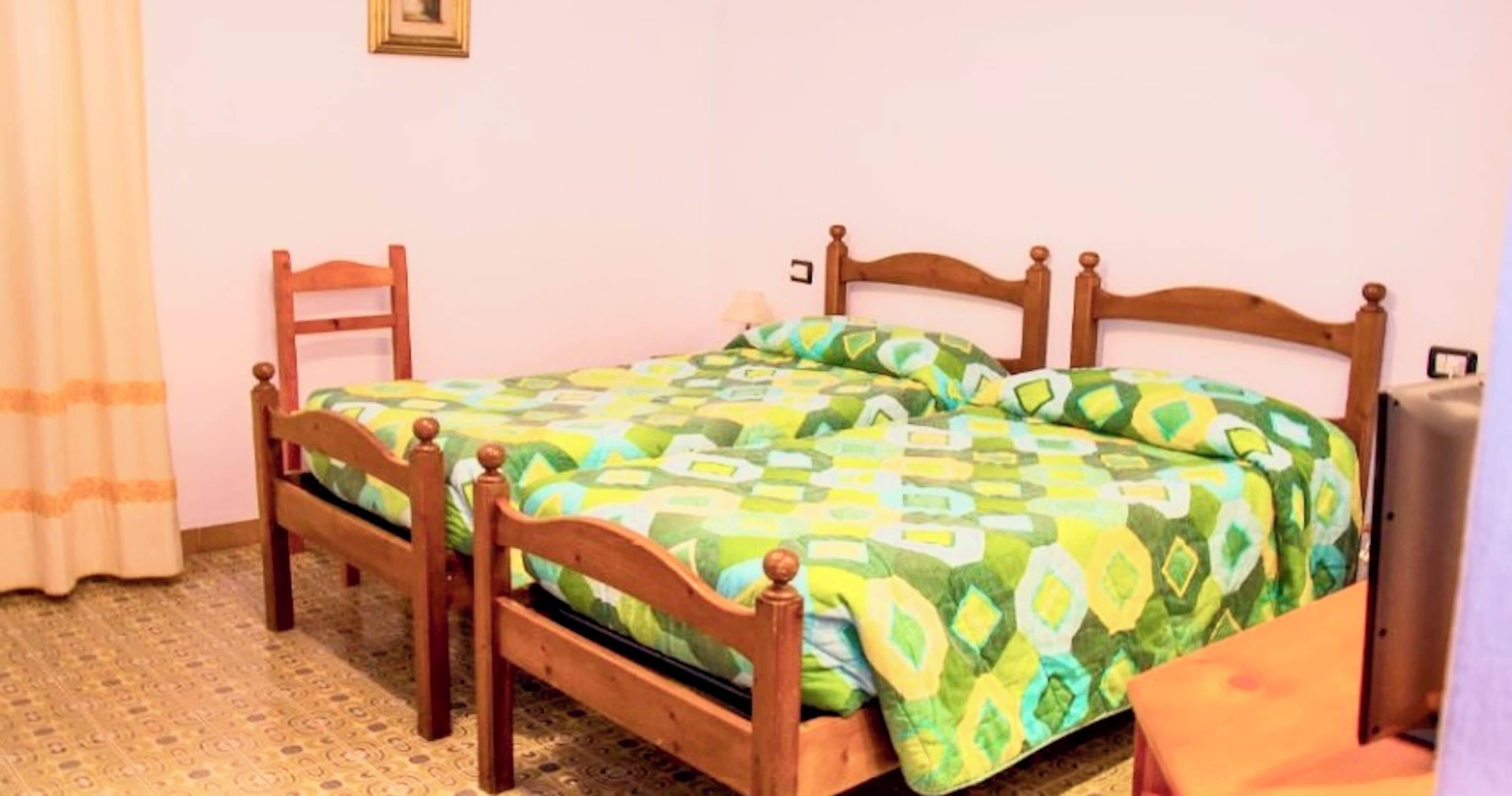 Una cama individual con estructura de madera y colcha estampada.