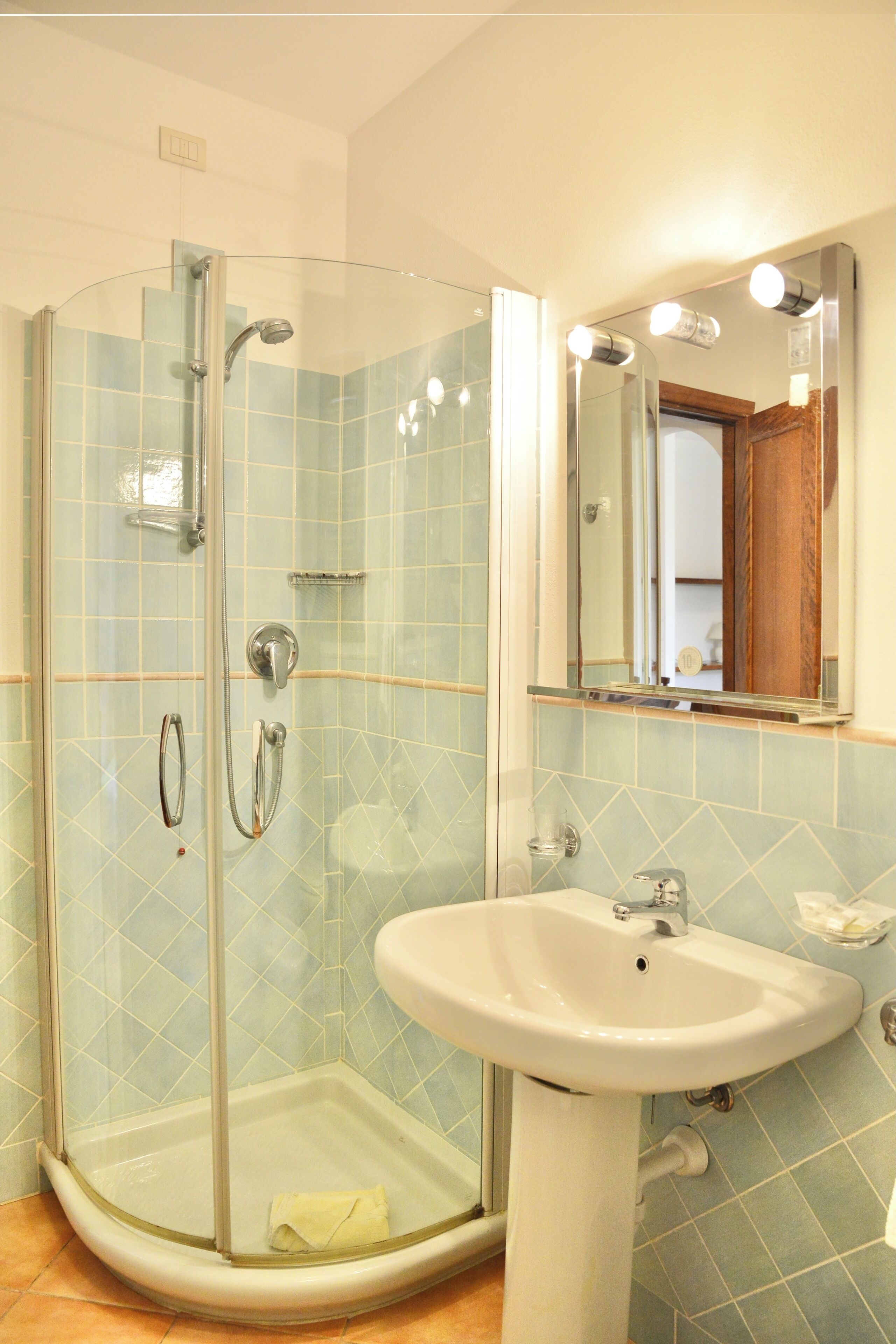 Une salle de bain avec une douche à parois de verre, un lavabo blanc et un miroir avec éclairage intégré.
