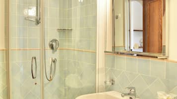 Une salle de bain avec une douche à parois de verre, un lavabo blanc et un miroir avec éclairage intégré.