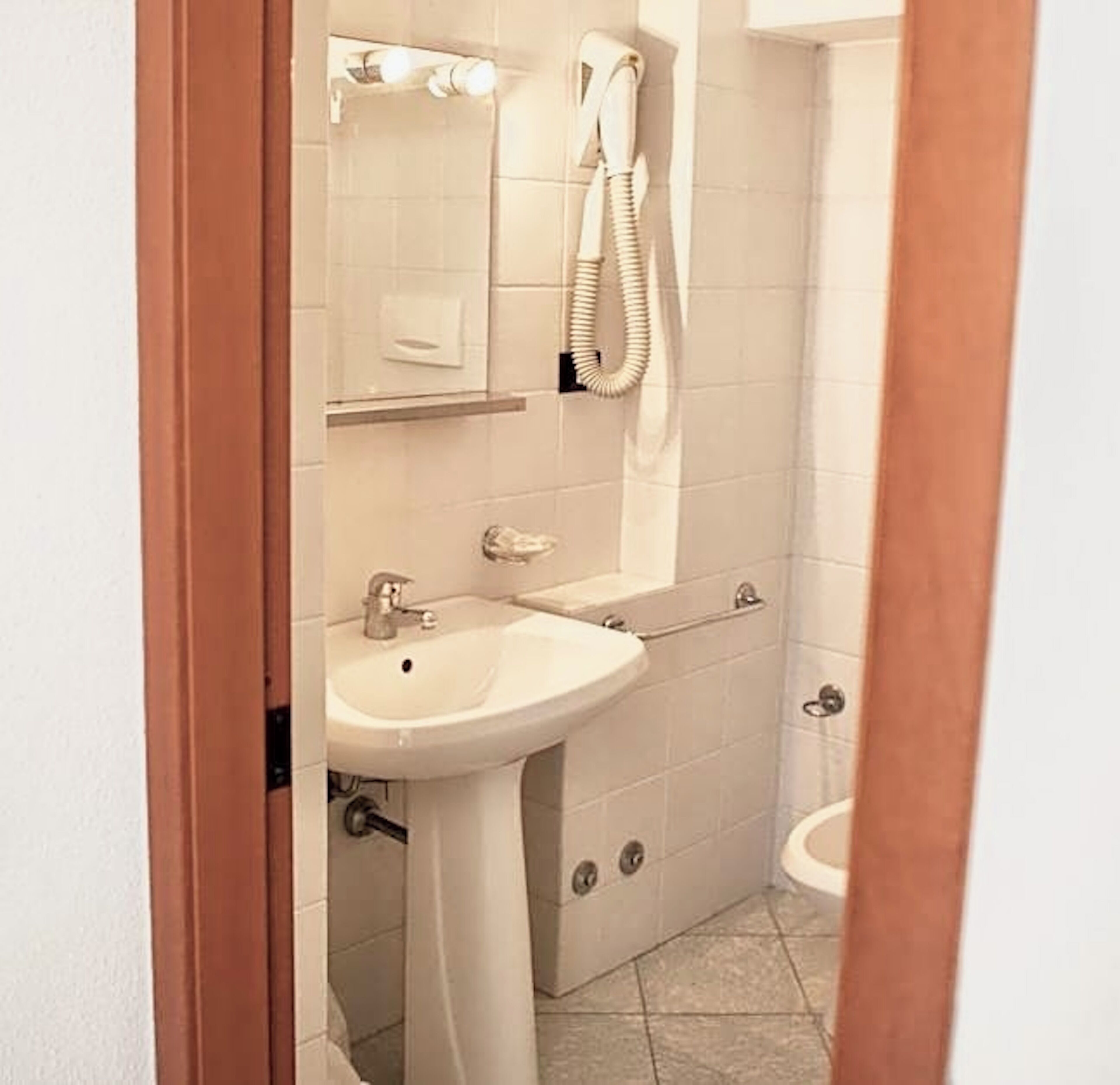 Een badkamer met een wastafel, spiegel en douche.