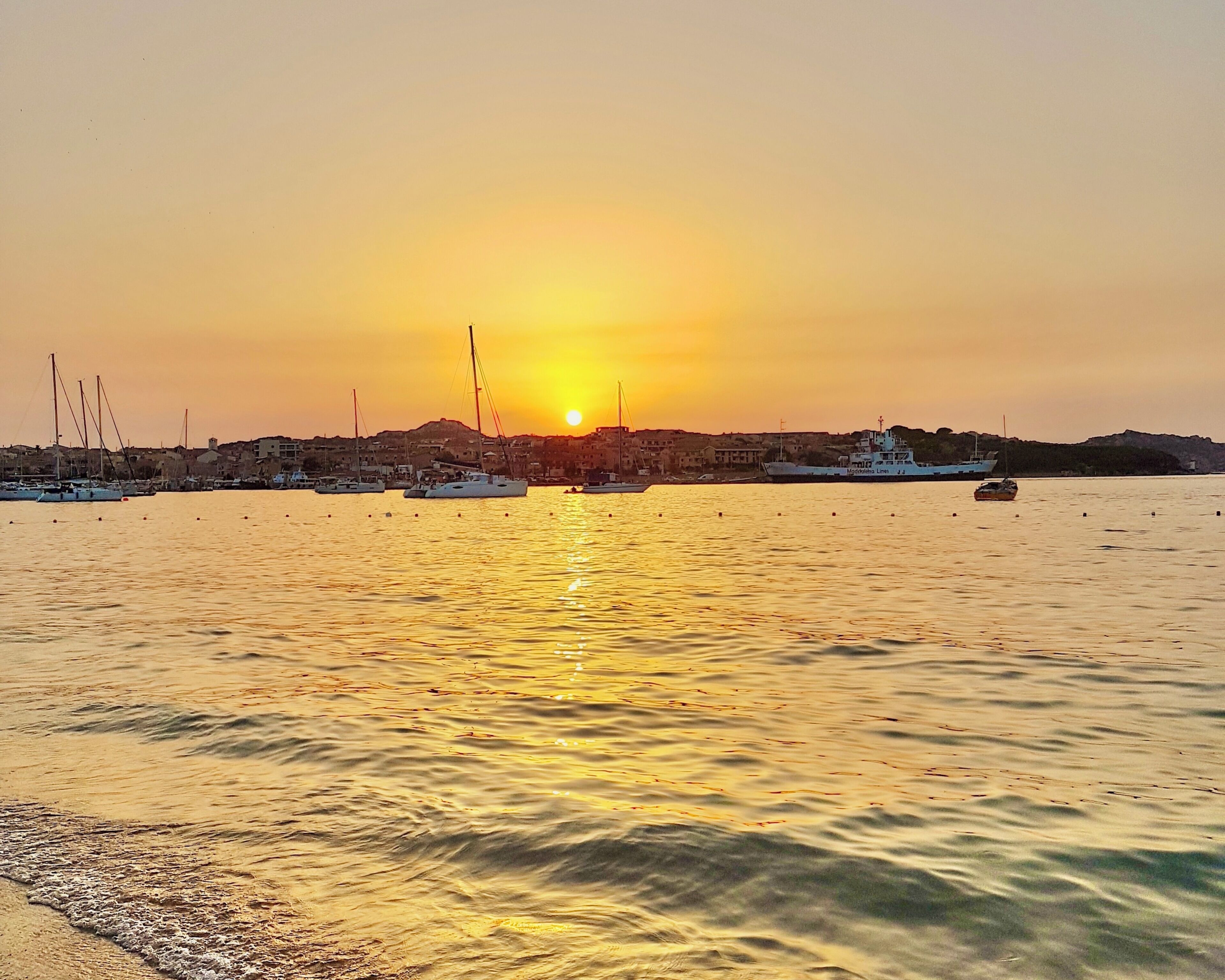 A sunset over a harbor with boats and buildings.
