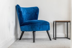 A chair with a high back and a solid seat, positioned against a white wall. - 4-Bed House | Leicester | Driveway Parking (Leicester)
