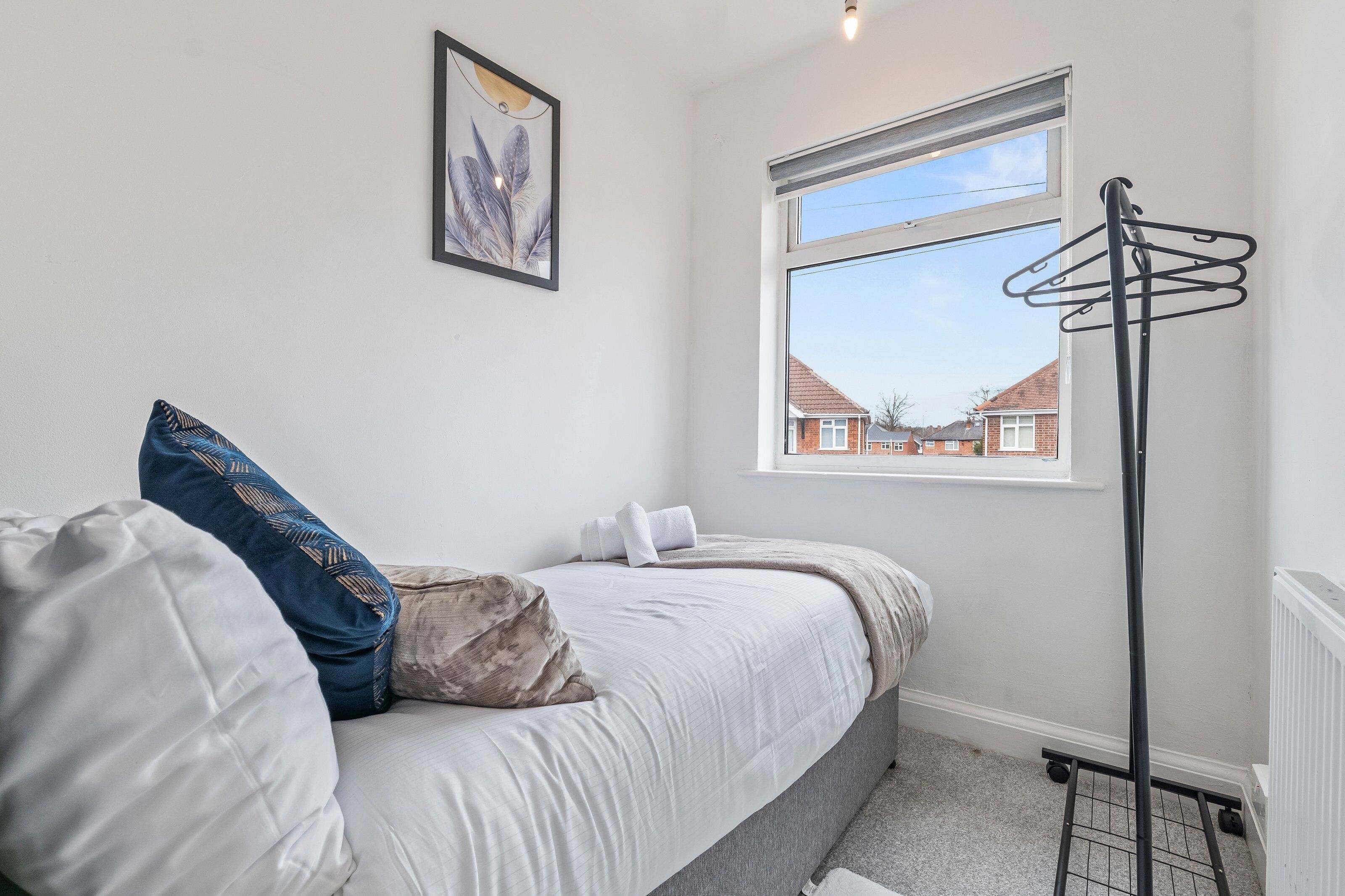 A bedroom with a bed, pillows, a window with a view, and a radiator.