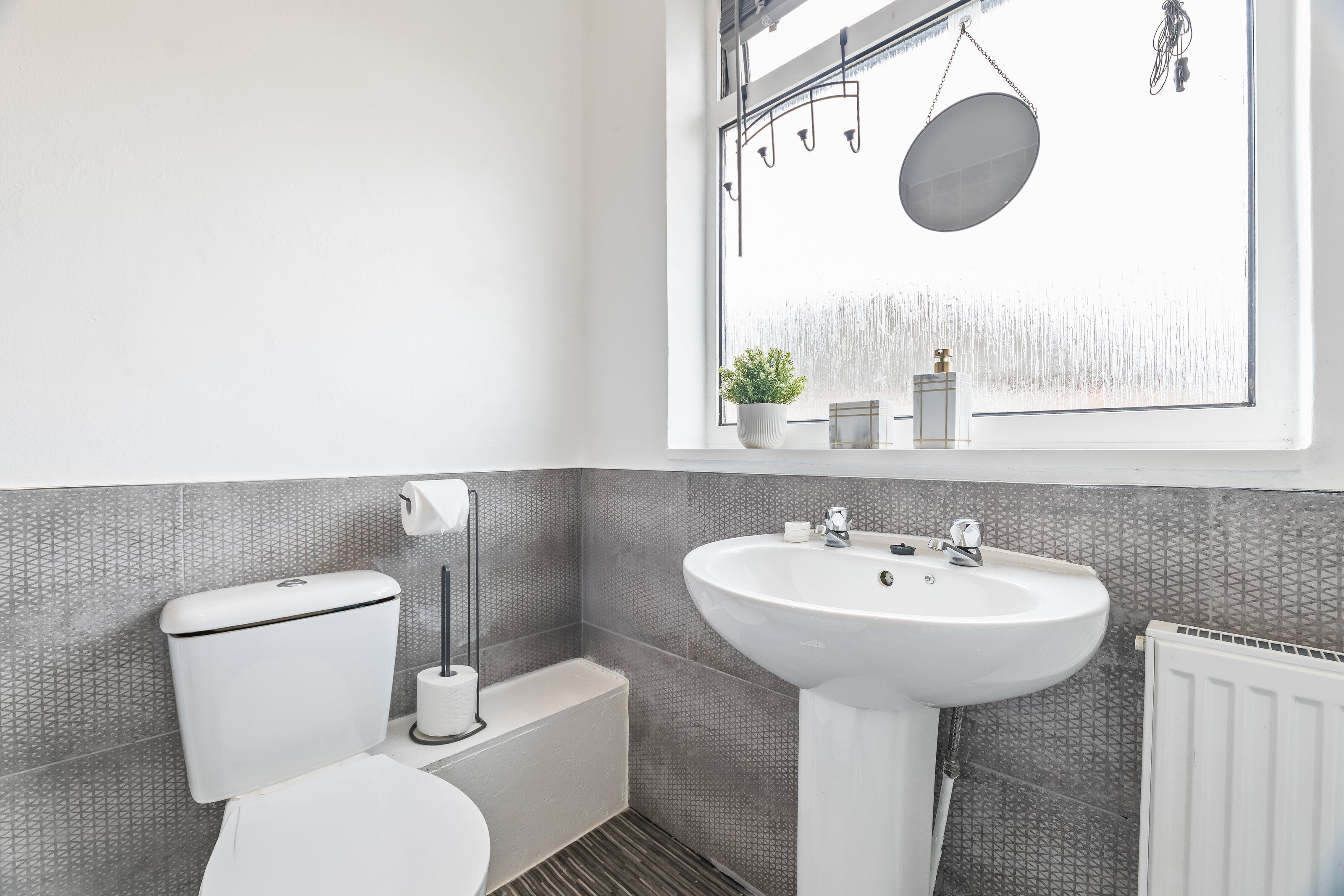 A modern bathroom with a toilet, sink, and a window with a view of a waterfall.