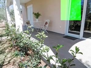 A modern outdoor seating area with a table and chairs, surrounded by greenery and a building entrance. - Vacation home Carina by Interhome (Poreč/Kaštelir)
