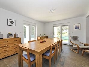 Una habitación amplia con una mesa de madera, sillas, un sofá y un ventilador de techo.