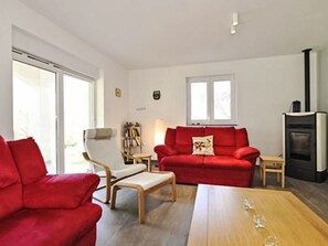 A living room with a red sofa, a white armchair, a wooden table, and a fireplace. - Vacation home Carina by Interhome (Poreč/Kaštelir)