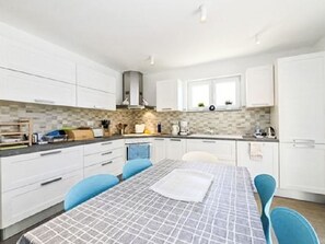 A modern kitchen with white cabinets, a central island, and blue chairs. - Vacation home Carina by Interhome (Poreč/Kaštelir)
