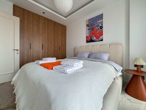 A bedroom with a bed, a wooden wardrobe, a painting, and a bedside table with a lamp. - Qoople Elize A39 - Cozy 1-bedroom apartment in Alanya (Alanya)