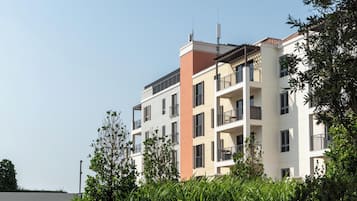 Um edifício residencial de vários andares com varandas, um telhado plano e céu claro.