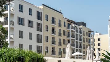 A multi-story hotel with balconies, outdoor seating, and a clear sky.