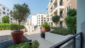 A courtyard with potted plants, a pathway, and multi-story buildings with balconies.