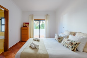 A bedroom with a bed, pillows, a dresser, and a window with curtains. - Praia Dona Ana Apartment (Lagos)
