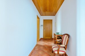 A hallway with a wooden door, a dining table with chairs, and a tiled floor. - Praia Dona Ana Apartment (Lagos)
