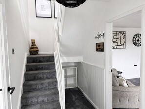 A staircase with a grey carpet, a woven basket, and a framed quote on the wall. - Hollow House | Modern Comfort in a Great Location (Barrow-in-Furness)