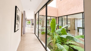 A corridor with a glass wall, a framed picture, and a plant. - Exceptional villa overlooking the Amelkis Golf Course - 6 bedrooms, hammam, and indoor pool (Marrakech)